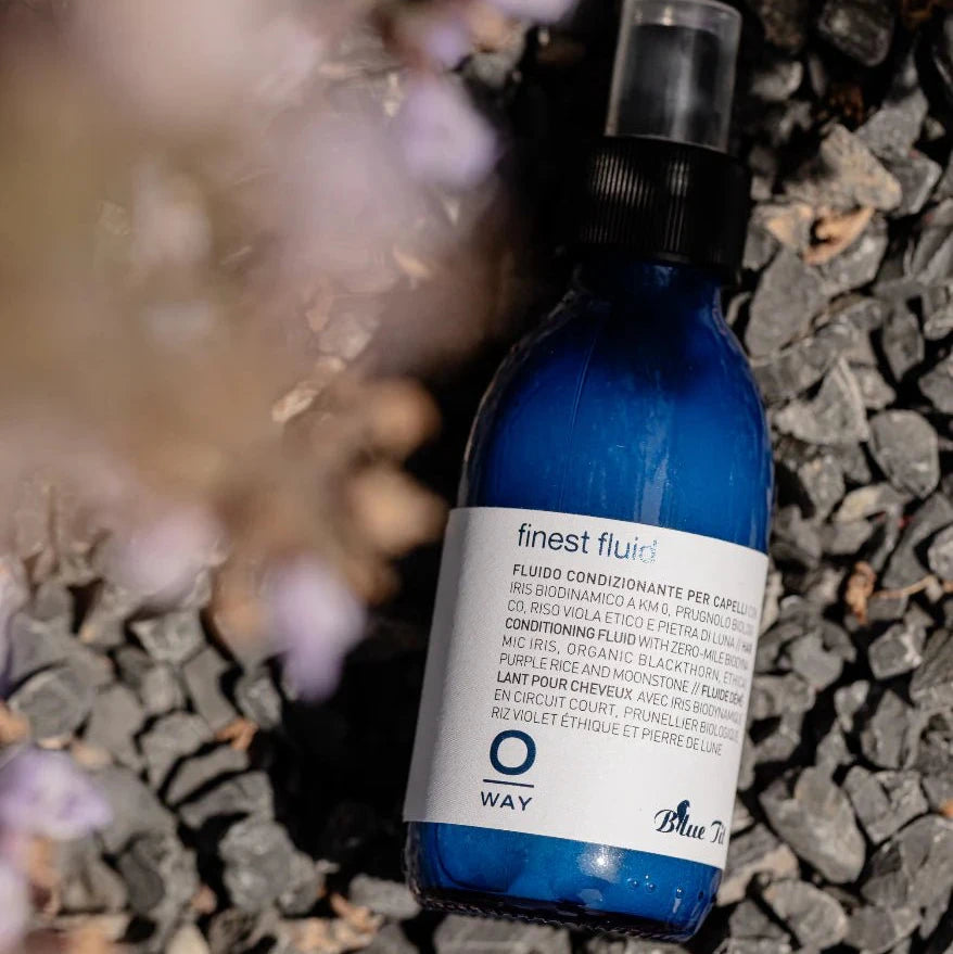 Blue bottle with label on a textured surface with blurred flowers in the background