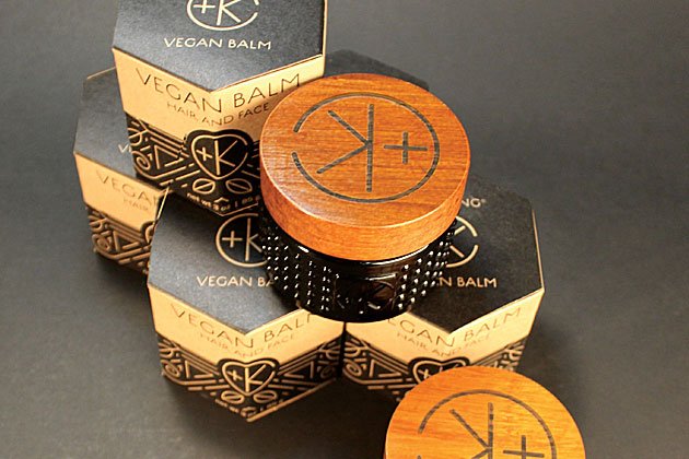 A wooden box with a logo, containing Cult and King VEGAN BALM | Manifest Moisture for Hair Styling and Face, sits on top of a black table.