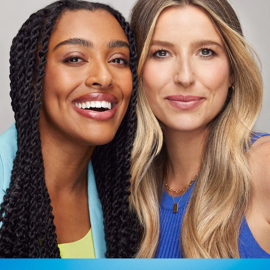 Two women smiling, one with long braided hair and the other with long wavy hair. Text overlay at the bottom reads, "Shield your healthiest hair against daily damage with K18 Damage Shield pH Protective Conditioner from K18 Hair Repair.
