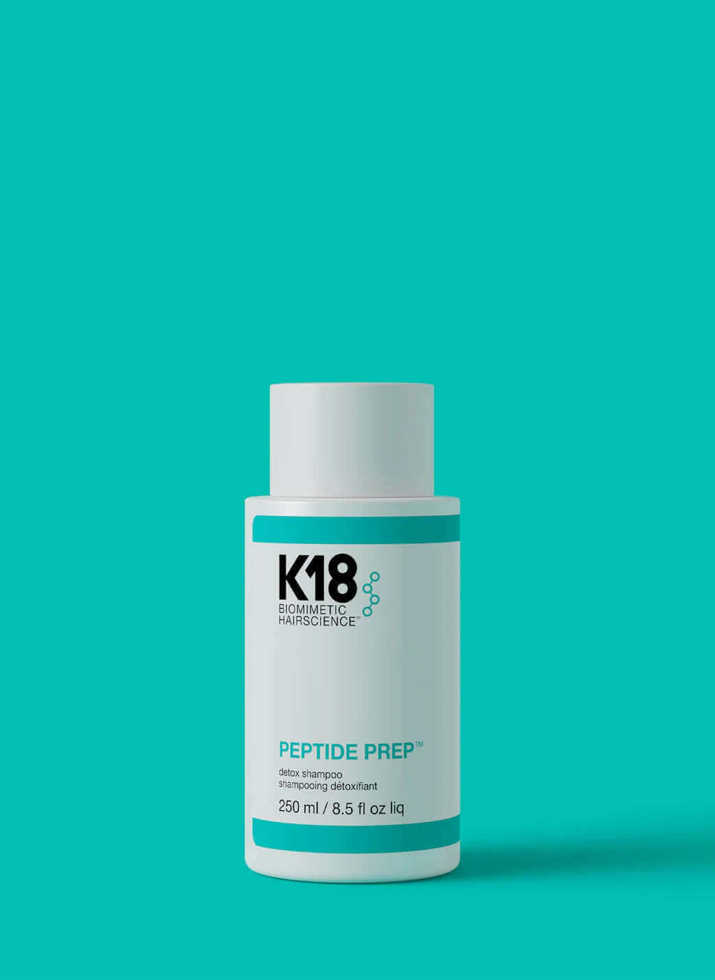 A white bottle of K18 PEPTIDE PREP Detox Shampoo - Multiple Sizes, a color-safe clarifying shampoo with deep cleanse properties, featuring turquoise accents on a matching background. The 250 mL (8.5 fl oz) bottle proudly showcases the K18 Hair Repair logo.
