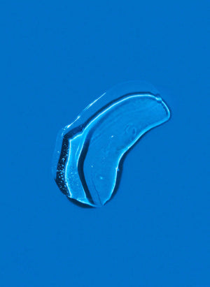 A single clear water droplet rests on a smooth, bright blue surface, reflecting the purity of K18 DAMAGE SHIELD pH Protective Shampoo from K18 Hair Repair.