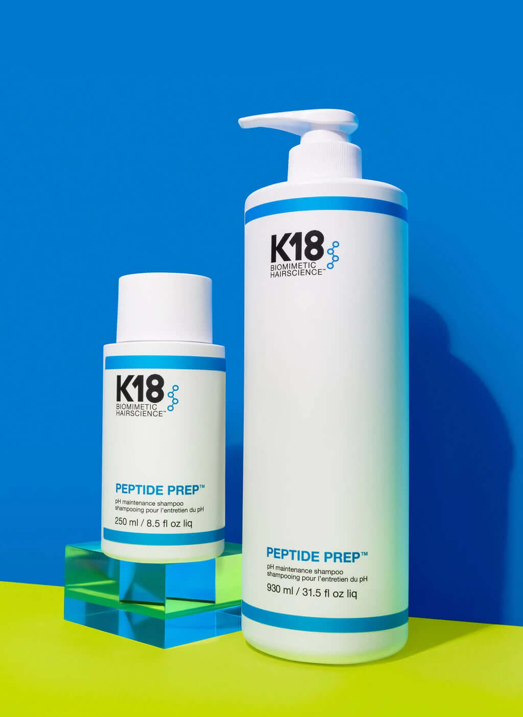 A bottle of pH-balanced K18 PEPTIDE PREP pH Maintenance Shampoo by K18 Hair Repair on a blue and yellow background.