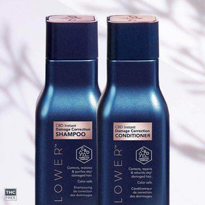 Two dark blue Leaf and Flower bottles, labeled "Instant Damage Correction Shampoo & Conditioner Duo," sit side by side. Infused with natural ingredients, this duo corrects damage and delivers color-safe care for dry, damaged hair.
